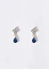 Aros colgantes de plata 925 con baño de oro 18k, con un diseño superior en forma de flor compuesto por circones transparentes y un colgante en forma de gota de circon color azul.