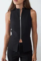 Chaleco negro de cuello alto con cierre frontal de cremallera plateada, corte entallado y confeccionado en tejido crepé.