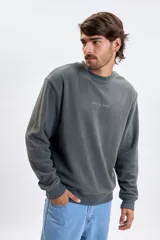Buzo de polar gris oscuro con cuello redondo, mangas largas y puños elásticos. Presenta un estampado minimalista con la frase 'coming soon' en el centro del pecho.