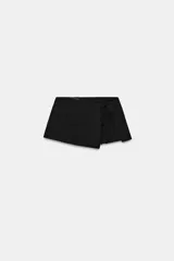 Falda pantalón corta de tiro medio, color negro, con diseño cruzado y detalle de lazada en el delantero.