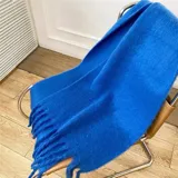 Bufanda de tejido suave y esponjoso en color verde intenso, con diseño de flecos largos en los extremos.