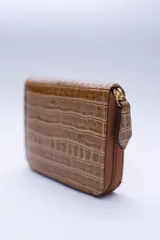 Billetera marrón tipo sobre con cierre de cremallera, confeccionada en cuero con textura tipo cocodrilo y forro textil rojo. Cuenta con múltiples ranuras para tarjetas, documentos y billetes.