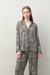 Camisa de pijama de silueta relajada, con estampado orgánico en tonos beige y negro. Cuenta con cuello camisero, cartera frontal con botones negros y vivos en contraste.