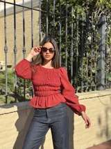 Blusa bordó con diseño fruncido mediante elásticos en el cuerpo y mangas largas abullonadas con puños elásticos.