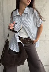 Camisa de manga corta con diseño a rayas celestes y blancas, cuello clásico y cierre frontal de botones.