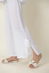 Pantalón palazzo blanco de lino italiano, con cintura elastizada y lazos de seda en los tobillos.