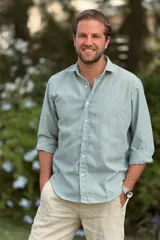 Camisa celeste con rayas verticales blancas, de lino, con cuello clásico y mangas largas con puños abotonados.