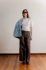 Pantalón sastrero de tiro medio con cierre frontal visto y bolsillos laterales. Presenta un diseño de corte recto y amplio con estampado floral sutil sobre fondo marrón.