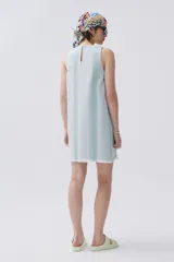 Vestido corto sin mangas de denim liviano a rayas verticales celestes y verdes. Cuenta con cuello redondo, abertura en la espalda y bajo desflecado.