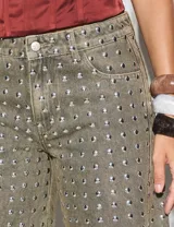 Pantalón de jean gris con tachas plateadas, corte recto y tiro alto.