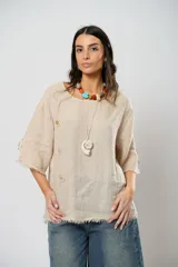 Blusa beige de lino con mangas 3/4 con lazos y detalle de flecos en los puños.