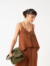 Top de viscosa color mostaza con escote en V y breteles finos regulables. Presenta un diseño minimalista de corte holgado y caída fluida.