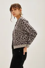 Cardigan de punto con estampado animal print en tonos gris y negro. Presenta cuello redondo con detalle de pedrería brillante, cierre frontal con botones y puños acanalados.