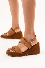 Sandalia de cuero color tostado, con plataforma y taco corrido, doble tira en la capellada con detalles de costuras decorativas y tira con hebilla ajustable en el talón.