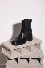 Botinetas negras de cuero con caña baja, punta cuadrada y cierre lateral con cremallera.