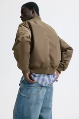 Campera bomber de nylon levemente acolchada, con cuello, puños y bajo acanalados. Presenta cierre frontal, bolsillos laterales con botón a presión y un bolsillo con cierre en la manga.