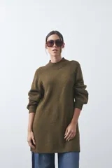 Vestido corto de punto en color beige, con cuello alto acanalado, mangas largas con puños ajustados y diseño holgado.