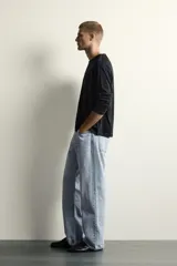 Jeans de denim de algodón en color azul con efecto desgastado, tiro medio y corte recto de ajuste holgado (loose fit). Cuenta con diseño clásico de cinco bolsillos y cierre frontal con cremallera y botón.