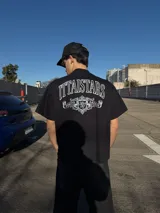 Remera negra de manga corta y corte oversize, con estampa gráfica en blanco en el frente y en la espalda con diseño de tipografía y escudo heráldico.