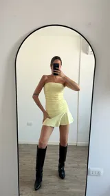 Vestido corto color amarillo pastel, strapless, con frunces laterales y falda con volados.