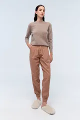 Pantalón estilo babucha color marrón, con pinzas en la cintura y puños elásticos en los tobillos.