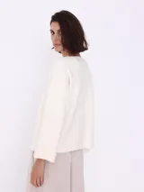 Sweater color crema de tejido de punto, con cuello redondo y prendedor de strass.