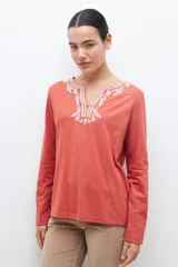 Remera blanca de manga larga con bordado floral azul en el escote.