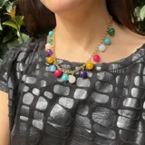 Collar dorado con cadena de eslabones y dijes colgantes de piedras naturales de diferentes colores.