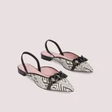 Ballerinas destalonadas modelo Clementine, confeccionadas en rafia con estampado étnico en blanco y negro. Forro y plantilla de piel con memory foam, taco de 1,5 cm y suela de goma antideslizante. Detalle de cadena plástica negra en el empeine.