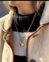 Collar de cadena de eslabones alargados con cierre frontal tipo T y dije circular de textura rústica e irregular.