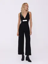 Mono largo negro con escote en V y detalle de lazo blanco en la cintura.