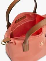 Cartera tote Tommy Hilfiger de nailon color salmón, con dos asas superiores de cuero sintético marrón y correa tejida extraíble. Cuenta con cierre de cremallera y detalle del monograma TH en metal dorado en la parte delantera.