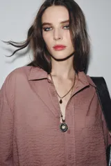 Pack de dos collares superpuestos. El collar más corto es de cadena de eslabones gruesos con un colgante de gota de cristal color vino. El collar más largo es de cadena fina con cuentas de cristal transparentes y cuentas facetadas color vino, terminando en un dije grande de flor en metal plateado con centro de strass.