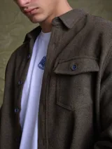 Overshirt de textura tipo tweed en color marrón, con cuello clásico, cierre frontal de botones y bolsillo en el pecho.