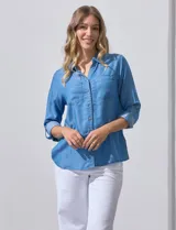 Camisa celeste de lyocell, con cuello a la base, escote en V y abertura central con botones. Tiene bolsillos aplicados en la parte delantera y mangas 3/4 regulables con presilla y botón.