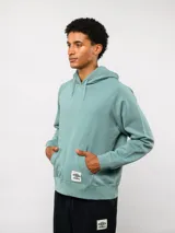 Canguro de felpa color verde menta, con capucha, bolsillo canguro frontal y etiqueta del logo Umbro en la parte delantera.