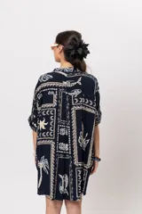 Camisa oversize azul marino con estampado de motivos marinos, palmeras y elementos geométricos en tonos claros. Presenta cuello mao y cierre frontal de botones.