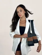 Bolso baguette de cuero negro con asa reversible y logo de la marca en etiqueta de cuero marrón.