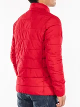 Campera puffer roja Calvin Klein, con cuello alto, cierre frontal con cremallera, bolsillos laterales con cierre, puños elásticos y logo en la manga.