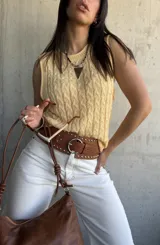 Chaleco amarillo de hilo tejido con diseño de trenzas, sin mangas y cuello redondo.