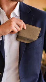 Billetera de cuero color marrón con textura granulada y detalle de franja horizontal en tono más oscuro con el logo grabado. Cuenta con múltiples compartimentos para billetes, tarjetas y visores.