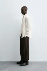 Camisa de corte regular fit confeccionada en tejido de algodón con textura de cuadrillé. Presenta cuello solapa, manga larga con puños abotonados y cierre frontal mediante botonadura.