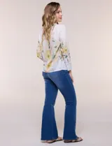Blusa de silueta holgada y corte recto con caída fluida, escote redondo y mangas largas con puños anchos estructurados, con estampado floral en tonos pasteles sobre fondo blanco.