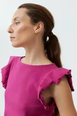 Top de punto canalé color fucsia, con cuello redondo y mangas cortas con volados decorativos en los hombros.