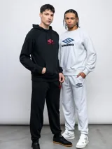 Pantalón jogger de felpa sin frisa, color gris claro melange, con logo bordado de Umbro en azul oscuro en el muslo izquierdo y puños elásticos en los tobillos.