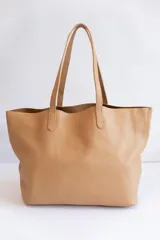Bolso tote de cuero color tostado, con doble asa de hombro y diseño minimalista. Incluye un bolsillo separador extraíble.