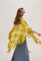 Chaleco tipo poncho tejido a crochet con diseño tie-dye en tonos amarillo y blanco, con flecos en el ruedo.