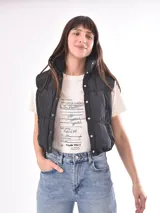 Chaleco negro con cuello alto y cierre frontal con botones a presión.