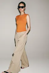 Pantalón de tiro medio confeccionado en hilatura de algodón, de corte wide leg y pernera ancha. Presenta cintura con trabillas, bolsillos laterales ocultos en costura, detalle de pliegues en la parte delantera y cierre frontal con cremallera, botón y ganchos metálicos.