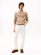 Sweater de punto Tommy Hilfiger con cuello en V, manga larga y puños y bajo acanalados. Presenta un diseño liso en color beige con el logo de la marca bordado en el pecho.